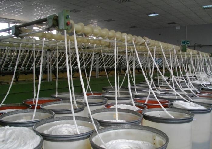 画像:綿花工場の紡績機械と、加工を待つ白い綿の束